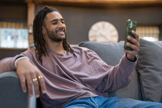Man with dreads taking selfie while relaxing on sofa model released Copyright: xCulturaxCreativex