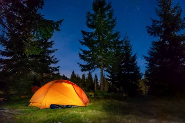 Orange illuminated tent in dark night forest with night sky and stars ,model released, Symbolfoto