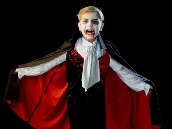 Portrait of boy wearing Halloween vampire makeup and costume cloak bared his teeth, isolated on black background. Boy wearing Halloween vampire costume ,model released, Symbolfoto