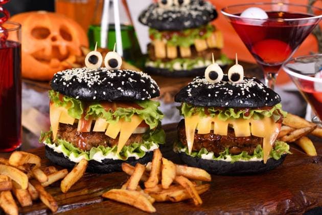Halloween Monster black burger Monster Burger. Black bun, juicy beef cutlet, lettuce, onion, tomato and cheese in the shape of teeth, mozzarella eyes with olives. Definitely a pick-me-up and a perfect Halloween party appetizer. Copyright: xZoonar.com VORONOVA_MARYNAx 21903740