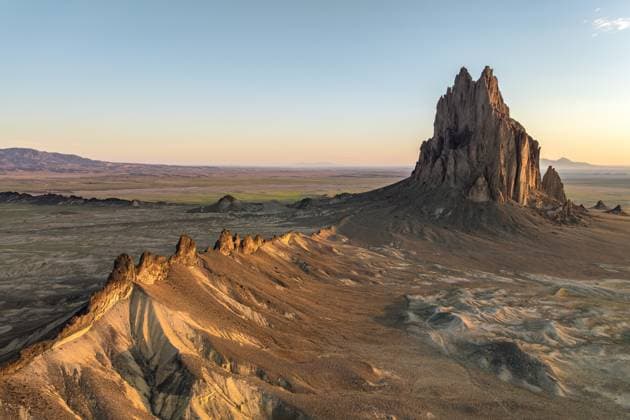 Scenic view of the iconic Shiprock rock formation bathed in golden sunset light against a vast desert landscape in New Mexico, United States. Model Released JuanLopez_ID22752_662547_004 Copyright: xJuanxLopezx