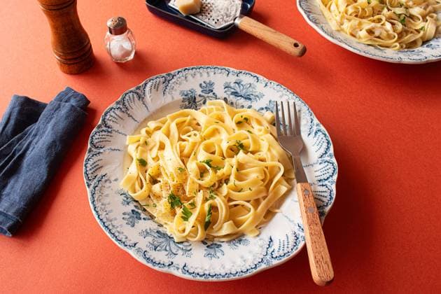 A close-up shot of fettuccine Alfredo on a red background. Garnished with fresh parsley and grated Parmesan cheese Model Released OlgaVila_ID22469_655933_005 Copyright: xOlgaxVilax RECORD DATE NOT STATED