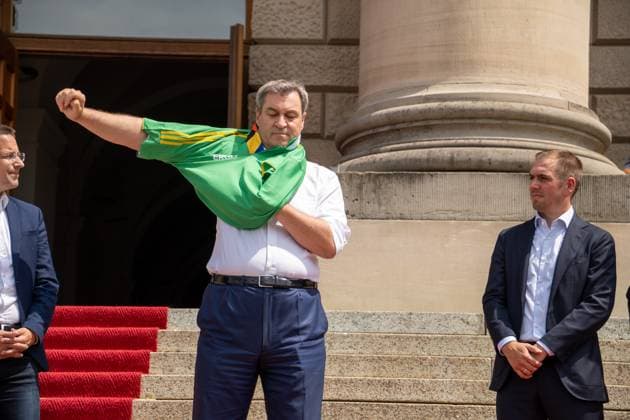 Ministerpräsident von Bayern Dr. Markus Söder bei der Ehrung der Freiwilligen Helfer der EM den Volunteers. Er zieht sich ein Volunteers Trikot an und steht neben Tunierdirketor Philipp Lahm