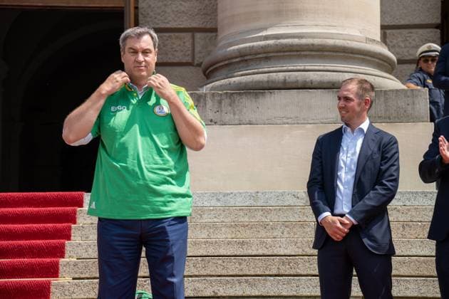 Ministerpräsident von Bayern Dr. Markus Söder bei der Ehrung der Freiwilligen Helfer der EM den Volunteers. Er zieht sich ein Volunteers Trikot an und steht neben Tunierdirketor Philipp Lahm