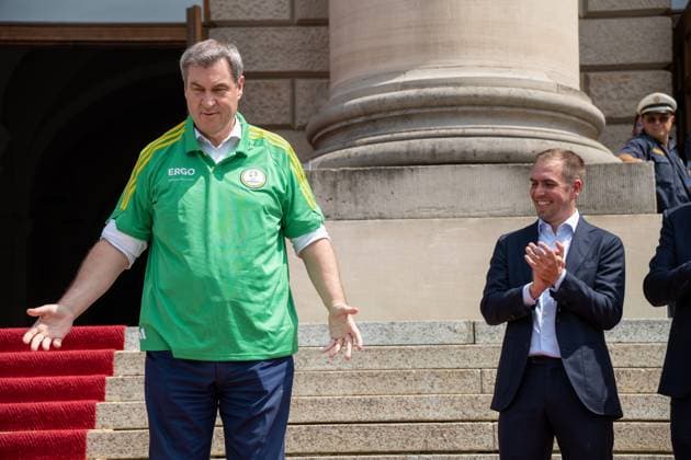 Ministerpräsident von Bayern Dr. Markus Söder bei der Ehrung der Freiwilligen Helfer der EM den Volunteers. Er zieht sich ein Volunteers Trikot an und steht neben Tunierdirketor Philipp Lahm