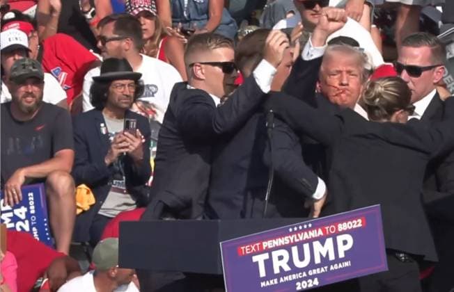 (240714) -- BUTLER, July 14, 2024 -- This video screenshot shows former U.S. President Donald Trump being helped off the stage at a rally in Butler, Pennsylvania of the United States after what sounded like gunshots rang out through the crowd, July 13, 2024. Video footage showed that Trump was making a speech when popping sounds rang out over the rally. Screams could be heard in the crowd, and Trump was swiftly escorted off the stage by Secret Service agents. Blood could be seen on the side of his head and his ear. He was quickly escorted into a vehicle, and his motorcade has left the venue. Trump is currently safe and is expected to survive, NBC News reported, quoting senior law enforcement officials. The shooting incident at Trum 