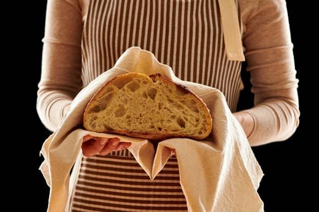 Baker woman holding rustic organic loaf of tartine homemade bread in hands ,model released, Symbolfoto
