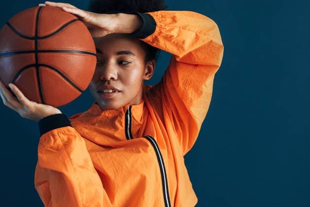 Creative Highlights Symbolbilder Close up studio shot of young female basketball player in orange sportswear posing with ball. Portrait of a professional basketball player over blue background. Close up studio shot of young female basketball player in orange sportswear posing with ball. Portrait of a professional basketball player over blue background. Copyright: xxArtemxVarnitsinx