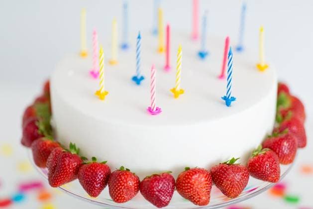 food, dessert and party concept - close up of birthday cake with candles and strawberries on stand. close up of birthday cake with candles on stand ,model released, Symbolfoto