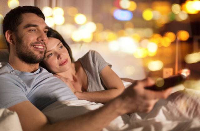 IMAGO Creative, Weihnachten, Tradition: Weihnachtsfilme sehen people, family and leisure concept - happy couple watching tv in bed at night at home. happy couple watching tv in bed at night at home ,model released, Symbolfoto