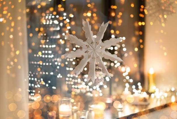 christmas and holidays concept - paper snowflake decoration hanging over garland lights and candles at night window. paper snowflake decoration hanging on window ,model released, Symbolfoto