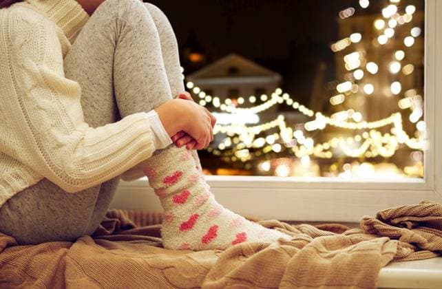 childhood, sadness and people concept - close up of girl in sweater sitting on sill at home window over christmas lights background. close up of girl sitting at window on christmas ,model released, Symbolfoto