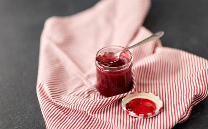 food, preserves and eating concept - mason jar with red raspberry jam with spoon on towel. mason jar with raspberry jam and spoon on towel ,model released, Symbolfoto
