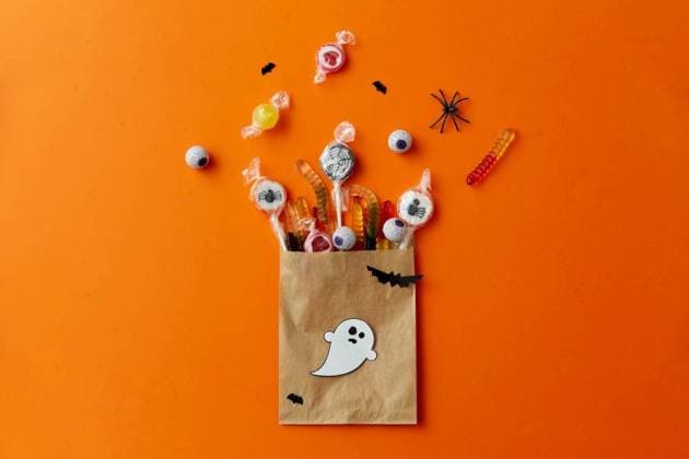 halloween, sweets and holiday concept - candies in paper bag and decorations on orange background. halloween sweets in paper bag on orange background ,model released, Symbolfoto