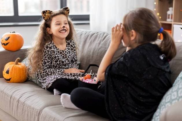 halloween, holiday and childhood concept - smiling little girls in party costumes sharing candies at home. girls in halloween costumes with candies at home ,model released, Symbolfoto