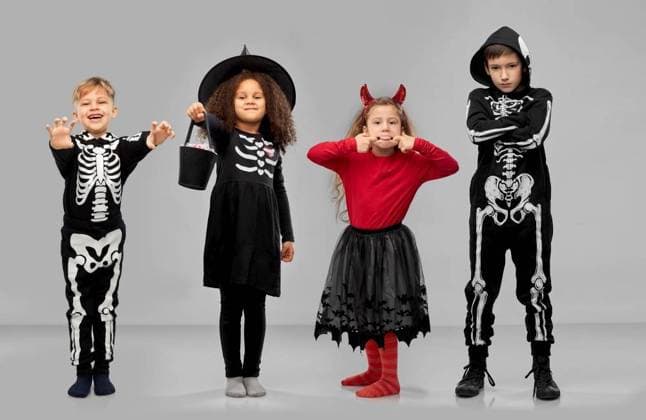 halloween, holiday and trick-or-treating concept - smiling children in carnival costumes making faces and playing trick or treat game over grey background. children in halloween costumes trick-or-treating ,model released, Symbolfoto