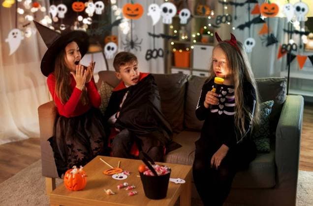 halloween, holiday and childhood concept - smiling boy and girls in party costumes playing with flashlight and scaring each other at home. kids in halloween costumes playing at home ,model released, Symbolfoto