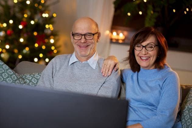 IMAGO Creative, Weihnachten, Tradition: Weihnachtsfilme sehen winter holidays, leisure and people concept - happy smiling senior couple watching tv at home in evening over christmas tree lights on background. senior couple watching tv at home on christmas ,model released, Symbolfoto