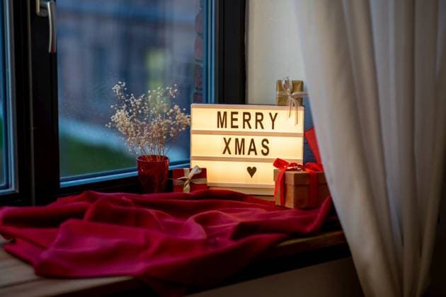 holidays, decoration and celebration concept - merry christmas greeting on light box and gift boxes on red tablecloth on window sill at home. merry christmas on light box and gifts on window ,model released, Symbolfoto