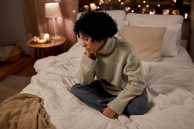 winter, comfort and people concept - sad woman in woolen sweater sitting on bed at home at night. sad woman in sweater on bed at home at night ,model released, Symbolfoto