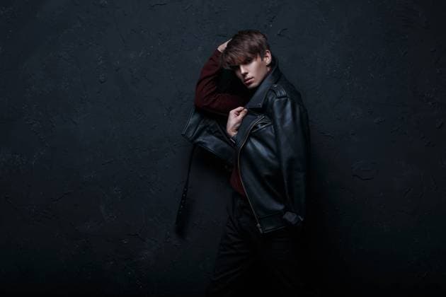 Modische coolen jungen Mann in einer schwarzen Lederjacke im Retro-Stil mit Burgunder stilvolle Golf und schwarze Jeans steht und posiert in einem dunklen Raum in der Nähe der schwarzen Wand. Gut aussehend Kerl *** stylish cool Boys Man in a Black people Leather jacket at Retro Style with Burgundy stylish Golf and Black Jeans is and poses in a dark Room in the Proximity the Black people Wall well looking Guy 1102808451