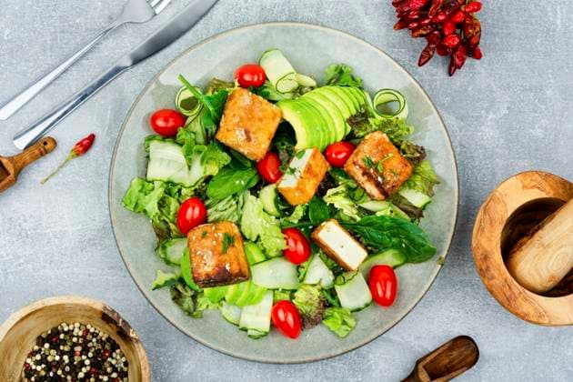 Appetizing lettuce salad, cucumber, avocado and breaded fried tofu soy cheese. Healthy lifestyle. Salad of roasted tofu and fresh vegetables, top view ,model released, Symbolfoto