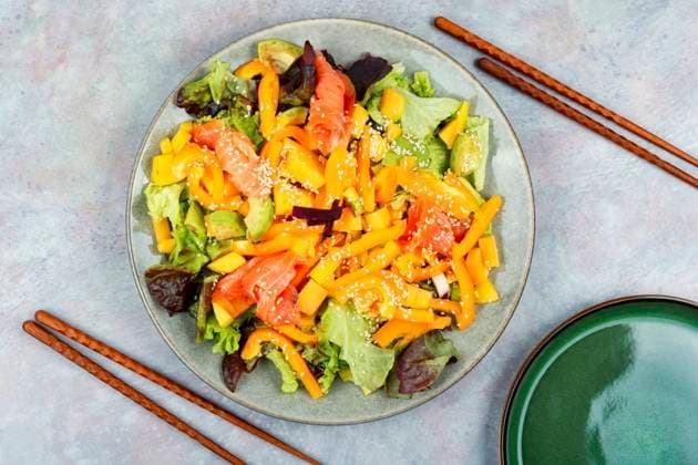 Tasty salad with salmon, mango, sesame avocado and pepper. Top view, food and chopsticks. Diet salad with salted salmon ,model released, Symbolfoto