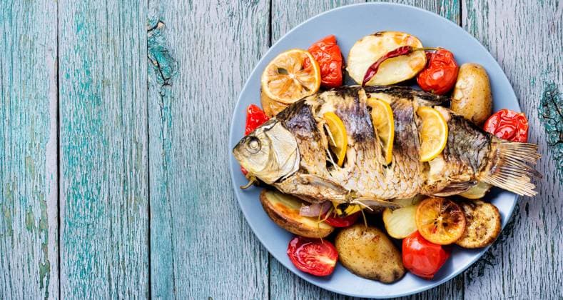 Grilled fish with potato and lemon on wooden table. Fish baked with vegetable garnish ,model released, Symbolfoto