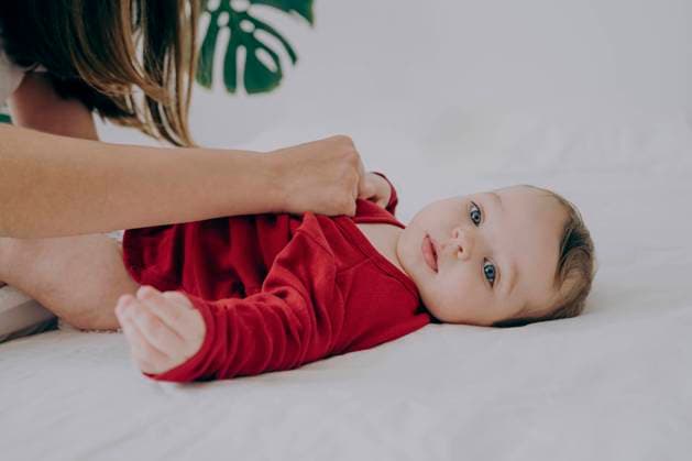 Creative Highlights Symbolfotos Baby boy lying on bed getting clothes changed by mother at home model released, Symbolfoto, AAZF01972