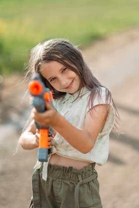Creative Highlights Symbolfotos Smiling girl playing with toy gun in back yard model released, Symbolfoto, ANAF03343