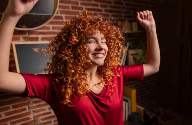 Creative Highlights Symbolfotos Happy redhead spectator cheering with arms raised at home model released, Symbolfoto, JCCMF12032
