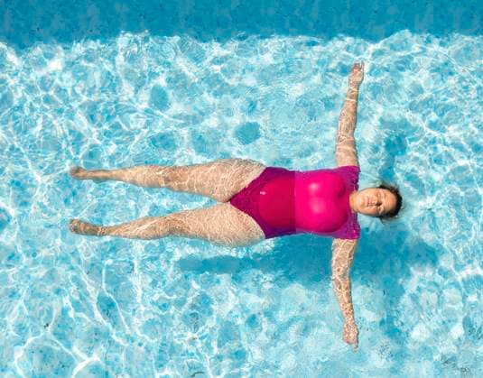 Creative Highlights Symbolfotos Mature woman floating and swimming in pool on sunny day model released, Symbolfoto, Breda Noord-Brabant Nederland Liesbos MKJF00908