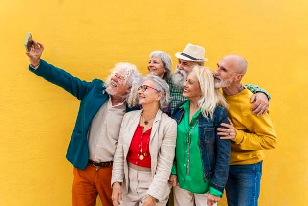 Happy senior man taking selfie with friends in front of yellow wall model released, Symbolfoto, OIPF04432
