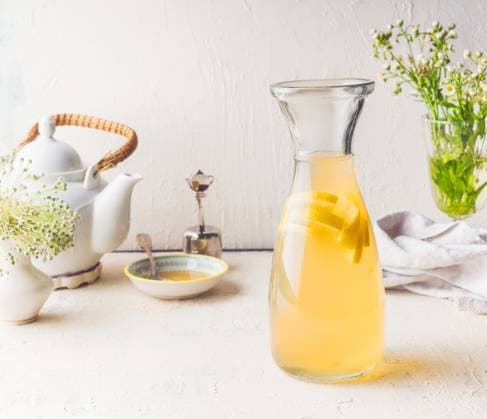 Carafe with white tea citrus lemonade drink on white kitchen table. Summer beverage concept ,model released, Symbolfoto