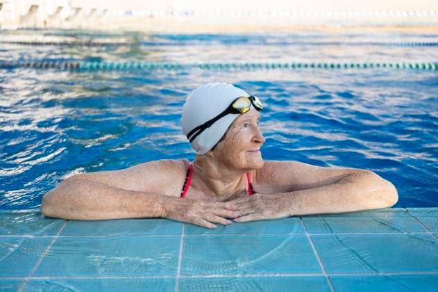 Creative Highlights Symbolfotos Contemplative senior woman in swimming cap and googles resting on edge of pool model released, Symbolfoto, VRAF00702