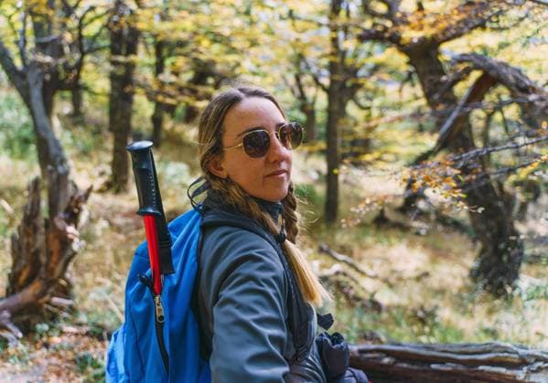 A woman wearing sunglasses on a log in a forest El Chaltén, Santa Cruz Province, Argentina CR_YBTM240722-1494054-01 ,model released, Symbolfoto