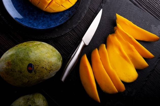 Ripe and tasty egyption Mango sleces and whole mango served at black dish. flat lay ,model released, Symbolfoto