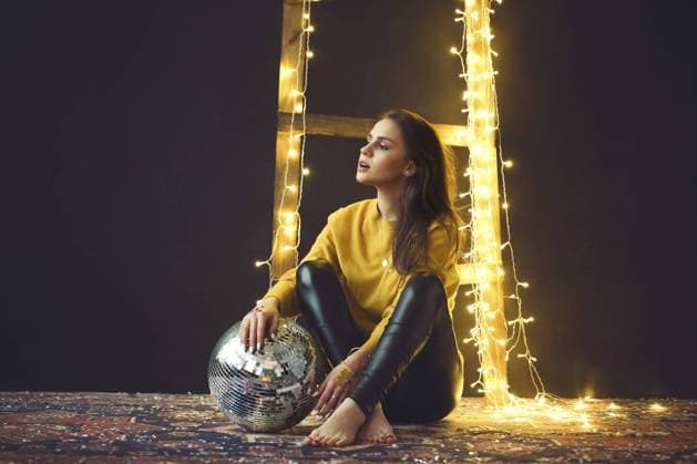 Creative Highlights Symbolbilder Beautiful young girl in yellow sweater holding disco ball near th wall with lights and shiny confetti on retro carpet Copyright: imageBROKER DashaxPetrenko ibxiqx10537315.jpg ,model released, Symbolfoto ,property released