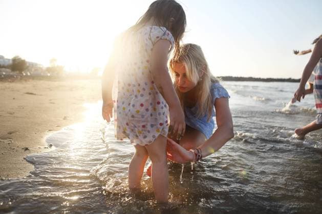 Creative Highlights Symbolbilder Young blond haired mother washing knees of her little daughter in colorful polka dots dress standing in sea on sunny summer day Copyright: imageBROKER DashaxPetrenko ibxiqx10539813.jpg ,model released, Symbolfoto ,property released