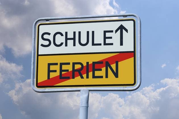 Symbolbild Schulstart: Auf einem Ortsausgangsschild stehen die Worte SCHULE und FERIEN (Composing) *** Symbolic image of the start of school The words SCHOOL and HOLIDAY are written on an exit sign Composing Copyright: xUdoxHerrmannx