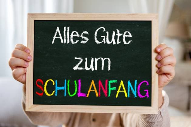 2 August 2024: Happy back to school! Congratulations on starting school. Child holding chalkboard with inscription: Happy first day at school. PHOTOMONTAGE *** Alles Gute zum Schulanfang! Glückwünsch zur Einschulung. Kind hält Kreidetafel mit Aufschrift: Alles Gute zum Schulanfang. FOTOMONTAGE