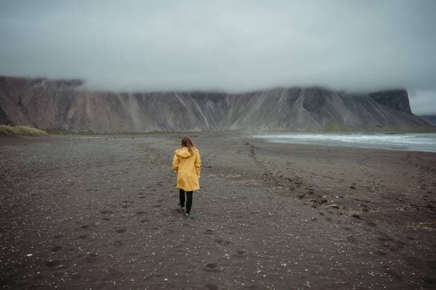 Creative Highlights Symbolbilder Woman walking on a rainy black beach in Stokksnes, Iceland. Nesjahverfi, Sveitarfélagið Hornafjörður, Iceland R_FFVO240801-1458863-01 ,model released, Symbolfoto