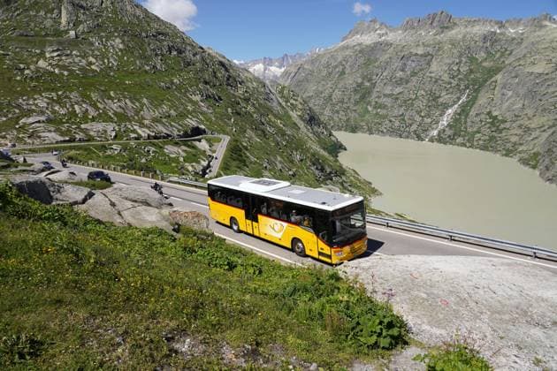 Anton Geisser 09.08.2024 Schweizer Postauto fahrt auf Alpenstrasse zum Grimselpass .Hinten der Grimselsee *** Anton Geisser 09 08 2024 Swiss Post bus driving on the alpine road to the Grimsel Pass Lake Grimsel in the background 