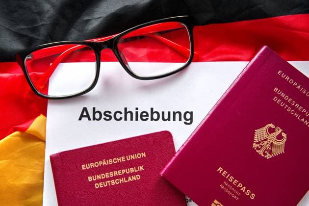 13 August 2024: A document with the title Abschiebung lies next to German passports and a pair of glasses on the flag of the Federal Republic of Germany *** Ein Dokument mit dem Titel Abschiebung liegt neben deutschen Reisepässen und einer Brille auf der Flagge der Bundesrepublik Deutschland
