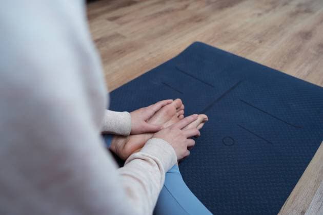 A person is captured from the back, sitting on a yoga mat in a meditation pose with hands on knees Model Released JUANAL~2 Copyright: xx RECORD DATE NOT STATED