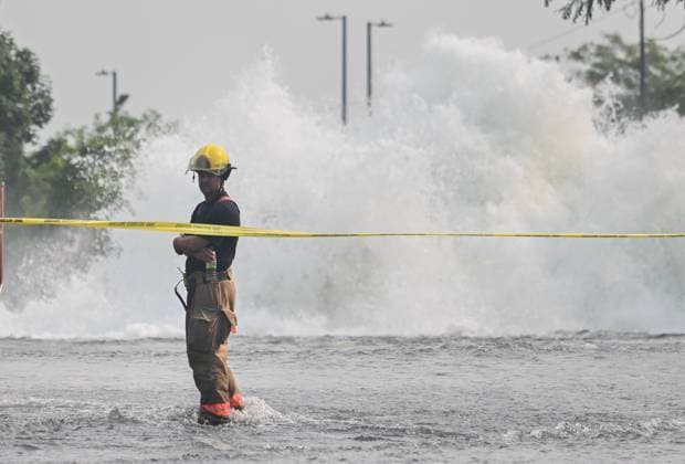 Kanada, Rohbruch sorgt für Überschwemmung in Montreal August 16, 2024, Montreal, Pq, Canada: A firefighter stands on a flooded street next to a geyser caused by a broken watermain in Montreal, Friday, August 16, 2024, causing flooding in several streets of the area. Montreal Canada  - ZUMAc35_ 20240816_zaf_c35_016 Copyright: xGrahamxHughesx
