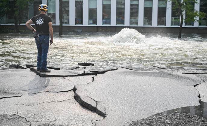 News Bilder des Tages Kanada, Rohbruch sorgt für Überschwemmung in Montreal August 16, 2024, Montreal, Pq, Canada: A person stands on cracked asphalt next to a geyser caused by a broken watermain on a street in Montreal, Friday, August 16, 2024, causing flooding in several streets of the area. Montreal Canada  - ZUMAc35_ 20240816_zaf_c35_019 Copyright: xGrahamxHughesx