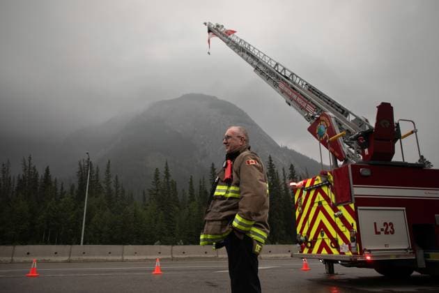 Kanada, Waldbrände in Alberta August 16, 2024, Jasper, Ab, CANADA: Hinton Fire Chief Mac de Beaudrap waits at the Park Gate with a Canadian flag to greet returning residents to Jasper, Alberta on Friday August 16, 2024. Wildfire caused evacuations and widespread damage in the National Park and Jasper townsite. Jasper CANADA  - ZUMAc35_ 20240816_zaf_c35_049 Copyright: xAmberxBrackenx