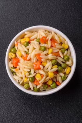 Delicious boiled rice with vegetables corn, carrots, peas with salt Delicious boiled rice with vegetables corn, carrots, peas with salt, spices and herbs on a dark concrete background Copyright: xZoonar.com TetianaxChernykovax 21995751