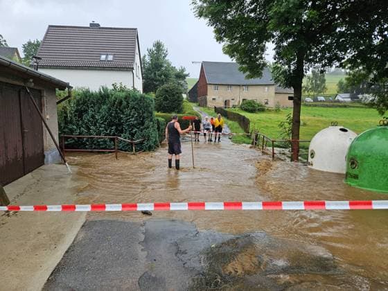 News Themen der Woche KW33 News Bilder des Tages 240818UnwetterOberscheibe Oberscheibe. Im Erzgebirge sind am Sonntagmittag heftige Unwetter gezogen. Stationäre Starkregengewitter brachten dabei sehr viel Regen auf engem Raum binnen kürzester Zeit. In Oberscheibe wurde der Abrahamsbach zum reißenden Strom und trat übder die Ufer. Auch in der Unterscheibe, Ortsteile von Scheibenberg, sah es nicht anders aus. Grundstücke an der B101 wurden durch den Abrahamsbach komplett überflutet. In Höhe der Bergstraße drohten ein Heizöltank und ein Gastank mit den Fluten mitgerissen zu werden. Die Feuerwehr kam hier zum Einsatz, um die Tanks zu sichern. In der Ortschaft gibt es zahlreiche Einsatzstellen nun abzuarbeiten. Unterstützt werden die Kameraden nun auch vom Bauhof mit Sandsäcken.